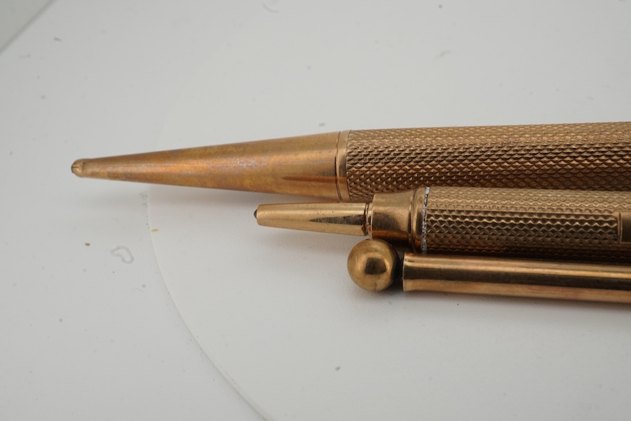 Two engine turned 9ct gold cased pencils including smallest by Sampson Mordan & Co, hallmarked for London, 1937, 7cm, the smaller with engraved inscription, together with a gold plated swizzle stick, larger pencil by E.